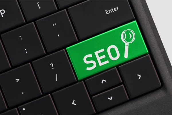 Green SEO button with a magnifying glass on a computer keyboard.
