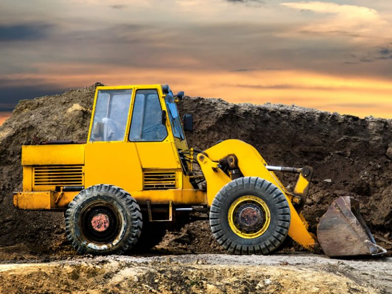 A front end loader construction vehicle on a construction site. Industries