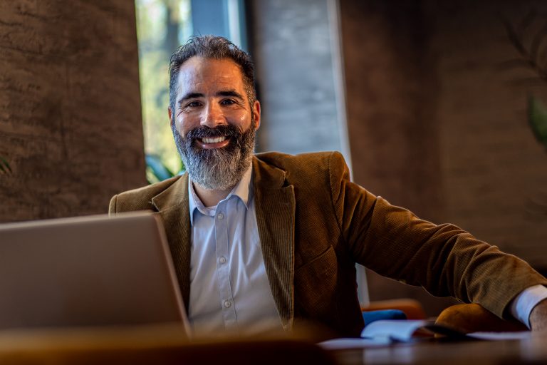 A man with a beard in front of a computer thinking about digital marketing for authors