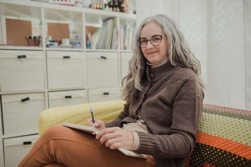 A woman with gray hair outside holding a notebook thinking about digital marketing for authors